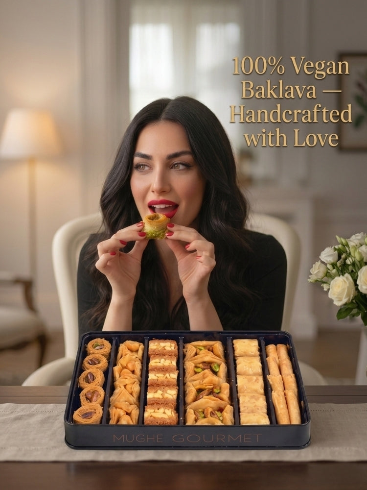 A woman holds a small baklava piece in front of a tray filled with assorted baked pastries. The scene is set in a softly lit indoor room with a chair, lamp, and flowers in the background.